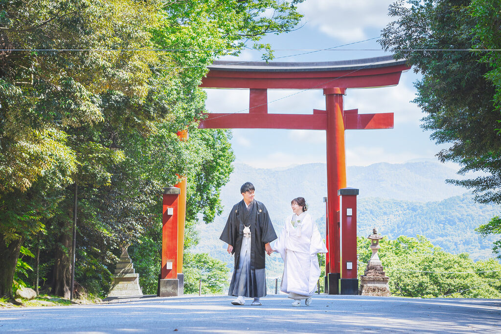 群馬県富岡市の貫前神社で、フォトウェディングのロケーション前撮り撮影をした和装写真で、大きな鳥居を背景にお二人で歩いてもらいました。